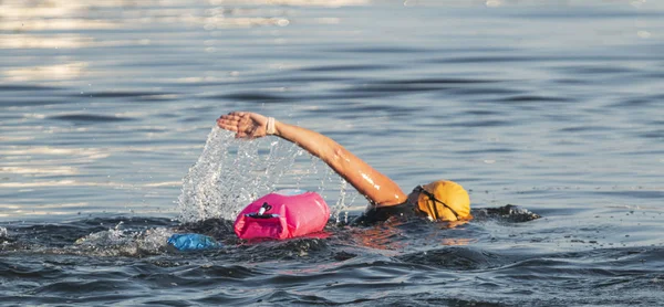 Nadar em águas abertas com dispositivo de flutuação rosa para segurança — Fotografia de Stock
