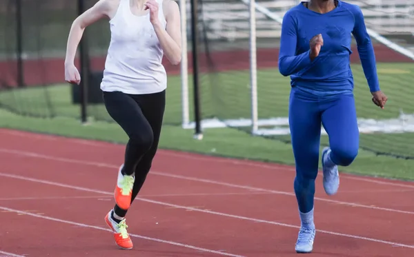 Two high school girls sprinters racing in the cold — Stock Photo, Image