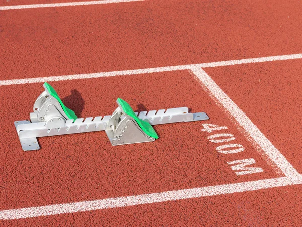 Green padded track and field starting blocks on a red track