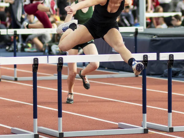High school girls racing the hurdles indoors — Stock Photo, Image