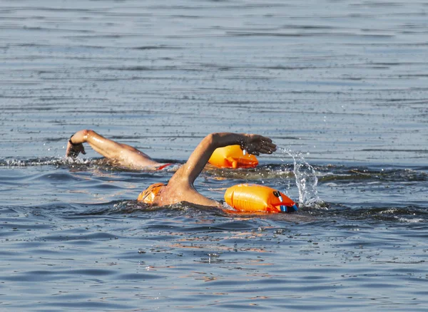 Turuncu güvenlik yüzdürme şamandıraları ile koyda yüzen iki adam — Stok fotoğraf