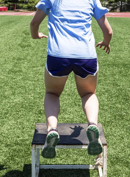 Visão traseira do adolescente realizando saltos caixa em um campo de relva — Fotografia de Stock