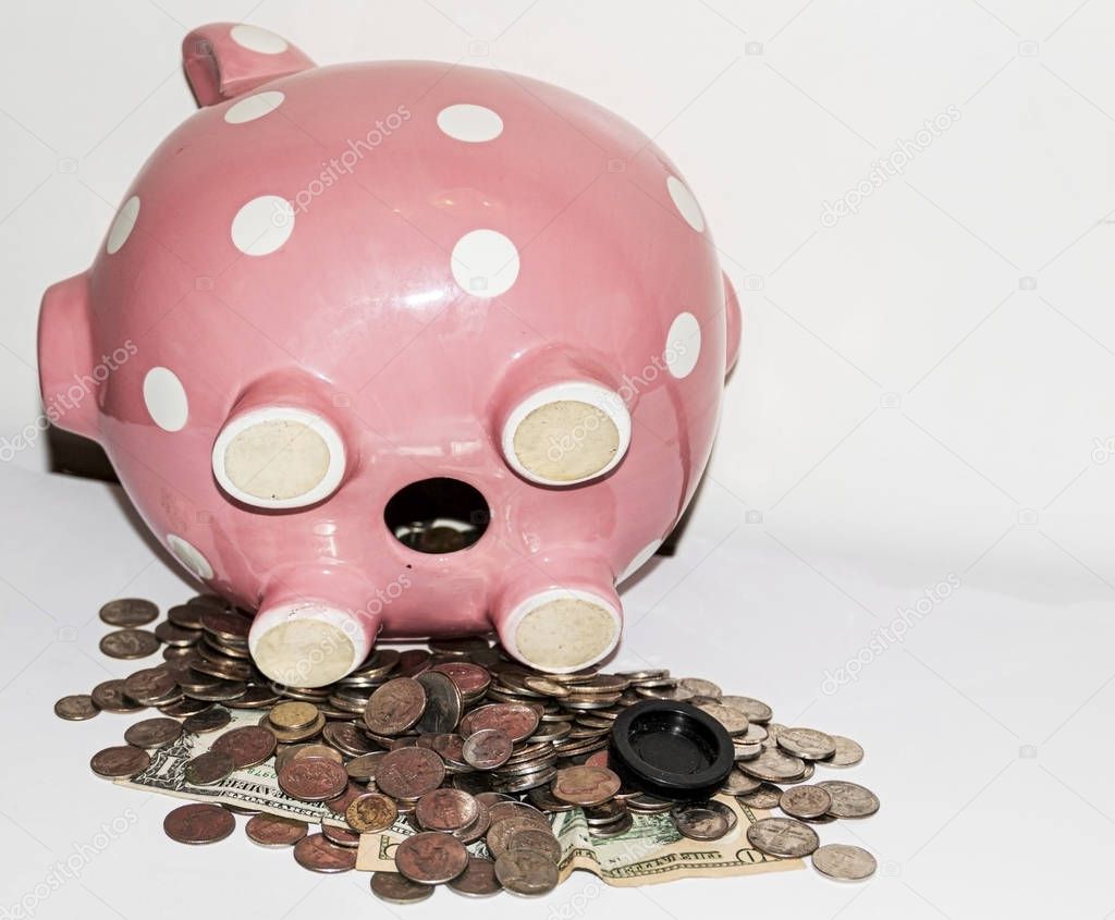 Pink piggy bank on its side with coins and bills falling out of 