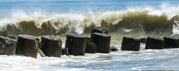 Landscaps view of large wave crashing above a jetty of rocks — Stock Photo, Image