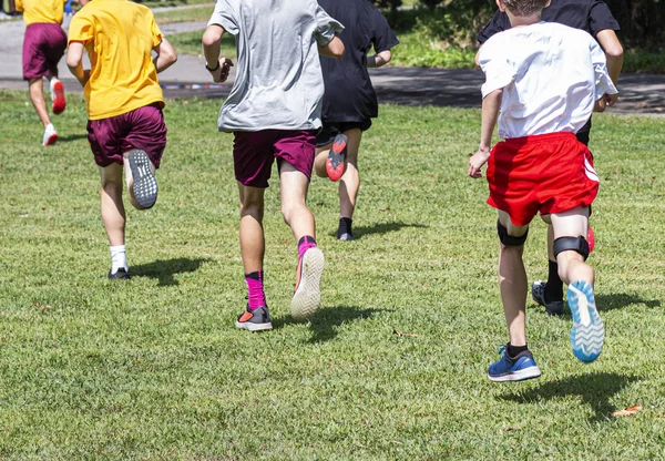 Achteraanzicht van jonge jongens die in een langlaufwedstrijd op gras rennen — Stockfoto