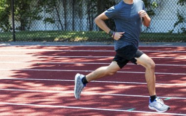 Koşucu kırmızı bir yolda gölgede hızlı çalışan