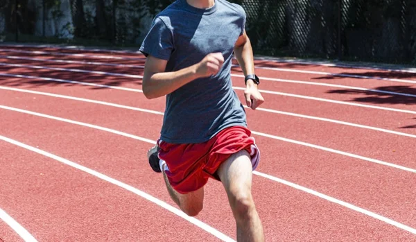 Front view of fast runner on red track in sunshine — Stock Photo, Image