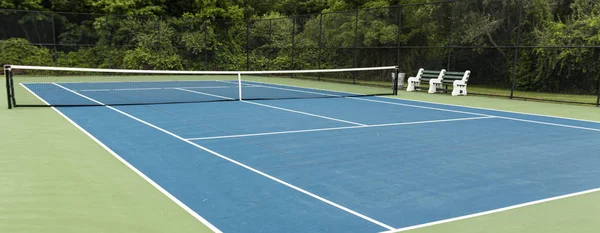 Vista Sie do campo de ténis azul com placa verde e bancos para — Fotografia de Stock