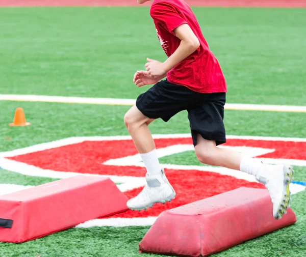 Mladý Chlapec Běhá Měkké Červené Bariéře Zeleném Hřišti Během Letního — Stock fotografie