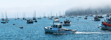 Rockport, Maine, ABD - 4 Ağustos 2017: Bir balıkçı teknesi sisli bir günde Maine Bar 'ında demirlemiş birçok yelkenli ve kayıp tekneler arasında hareket ediyor.