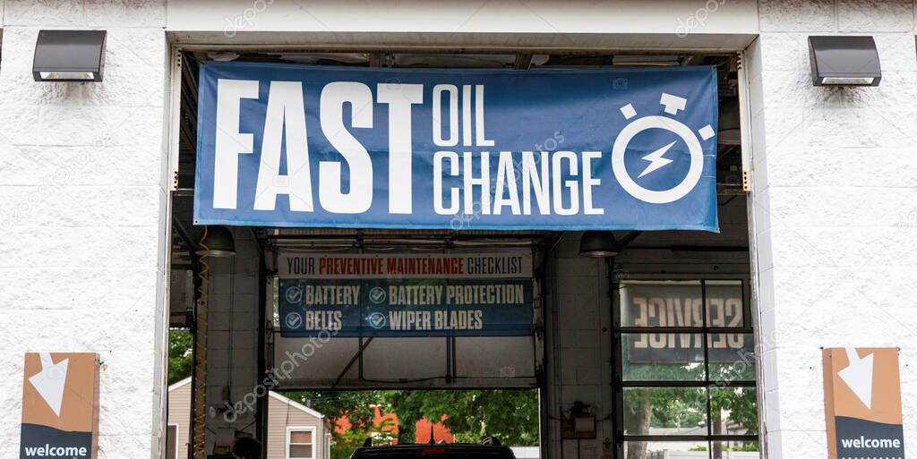 Large blue Fast Oil Change sign hangs over mechanics bay door with another sign reading preventative maintenance checklist at the exit.