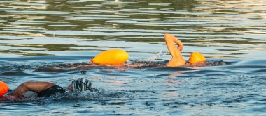 Bir kafe ve bir Afrikalı Amerikalı yüzücü denizde triatlonlara hazırlanmak için yan yana yüzüyorlar..