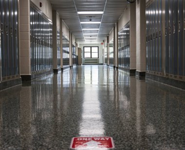Okul koridoru boş, yere tek yönlü tabela yapıştırılmış. Salgın hastalıklı okullar açmak için normal bir gereksinim..