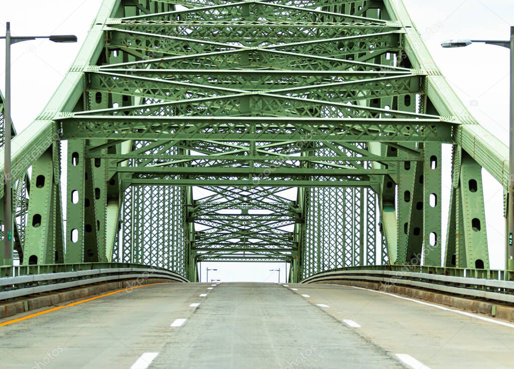 View of driving on a three lane highway up a bridge approaching its apex with no cars on the road travelling back from Fire Islnad to the mani land of Long Island New York.