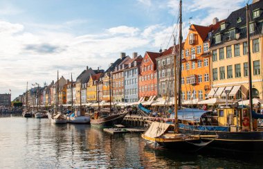 Nyhavn, Kopenhag, Danimarka - 2 Ağustos 2025: Kanal boyunca uzanan renkli evler, Kopenhag kıyılarında huzur içinde dinlenen tekneler.