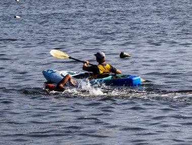 Bir kanocu, yanında su sıçratan bir yüzücünün yanındaki yumuşak suda yüzer..