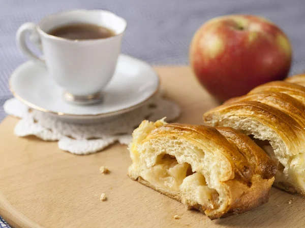 Bir elma ve bir fincan kahve ile dilimlenmiş elmalı turta masada yatıyor