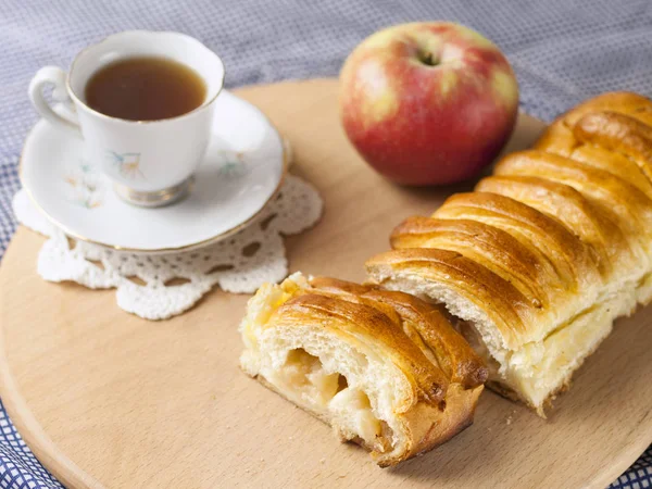 Bir elma ve bir fincan kahve ile dilimlenmiş elmalı turta masada yatıyor