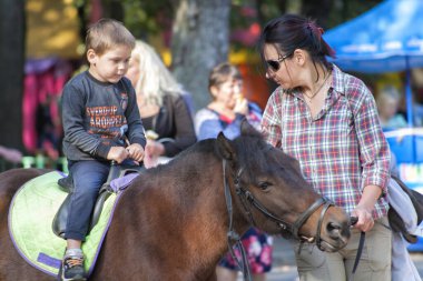 Vinnitsa, Ukrayna 14 Eylül 2019, annesi oğlunu küçük bir midilliye bindirdi.