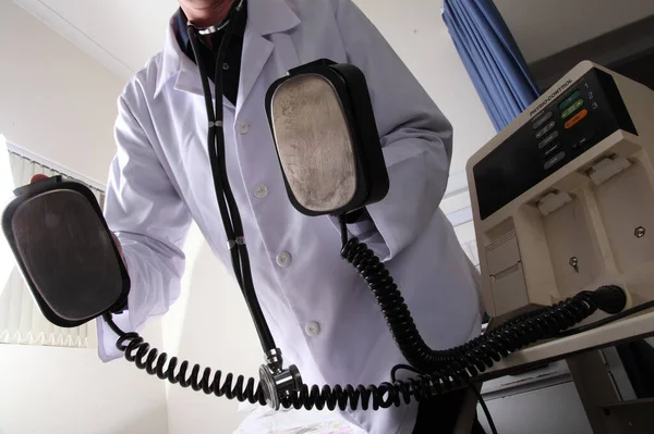 Defibrilatörden şok aletleri tutan bir doktor.