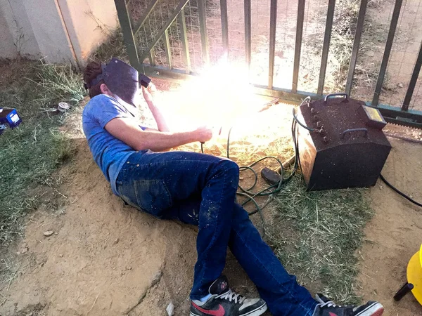 Kapıda kaynak yapan genç bir adam.