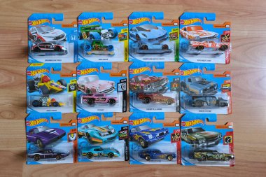 Istanbul, Turkey - July 29, 2020 : 12 Hot Wheels die cast toy cars in blisters on wooden floor from directly above view . clipart