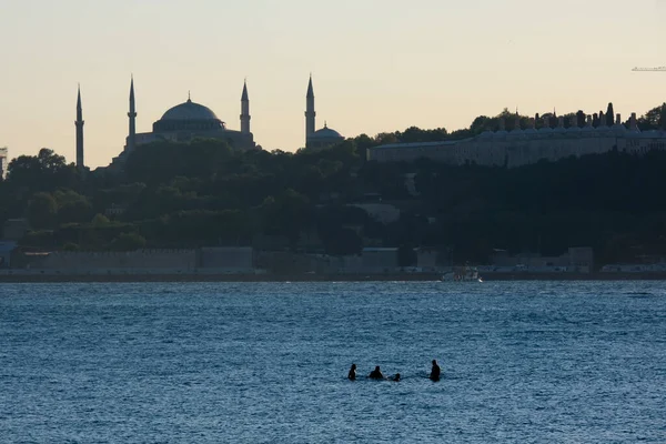 İstanbul, Türkiye - 1 Eylül 2020: İstanbul Boğazı 'nın ortasında dikilen dört adam var ve bu tuhaf görünüyor. Arka planda Ayasofya ve Topkapı Sarayı görünüyor..