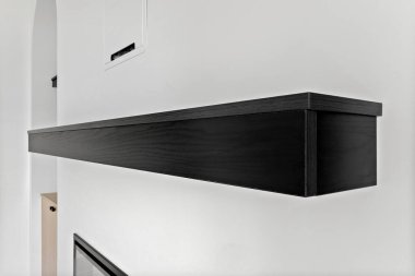 Siyah raf beyaz bir duvarda. Raflar boş.