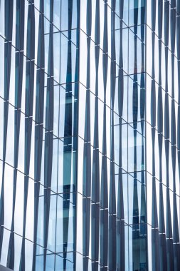 Bir sürü penceresi olan yüksek bir bina. Pencereler hareket ve derinlik hissi yaratacak şekilde düzenlenmiş. Bina camdan yapılmış gibi görünüyor, bu da ona modern bir...