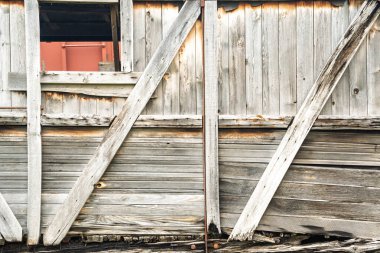 Penceresi ve kapısı olan ahşap bir bina. Ahşap eski ve yıpranmış, binaya kırsal ve büyüleyici bir görünüm veriyor. Pencere biraz açık.