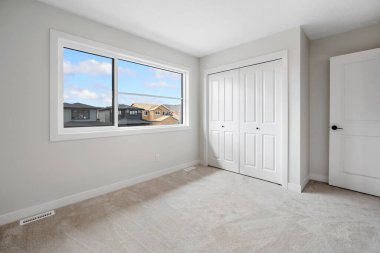 Penceresi ve dolabı olan bir yatak odası. Pencere açık ve oda boş.