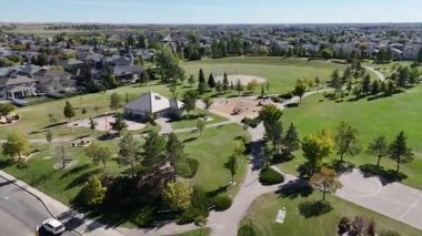 4K aerial view of Briarwood in Saskatoon during autumn, showcasing colorful trees, upscale homes, and parks in this established southeast neighborhood.