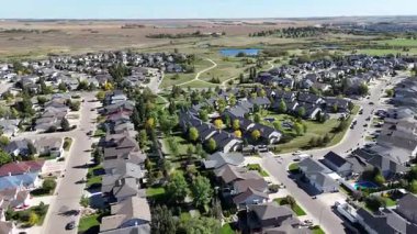 4K aerial view of Briarwood in Saskatoon during autumn, showcasing colorful trees, upscale homes, and parks in this established southeast neighborhood.