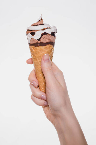Свободный образ жизни удовольствие концепция. Вертикальное крупным планом фото вкусного вкусного вкусного мороженого в хрустящей руке женщины с вафельным конусом, держащей изолированные на белом фоне вырезанное пространство для копирования
