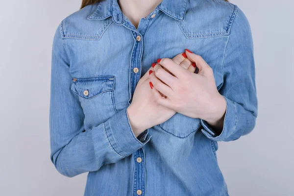 First symptoms of problems with heart concept. Cropped close up photo of sad unhappy upset lady holding hands on chest isolated on gray background copy-space