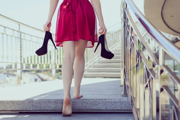 Follow me classic chic classy clothing after dancing prom concept. Gorgeous cute happy teen student holding black stilettos pumps in hands standing ground without shoes relaxing having rest chill out