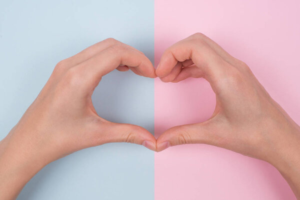 Забота об образе жизни одно целое понятие. Сверху над головой под высоким углом крупным планом фотография женских рук, дающих большое сердце с руками, изолированными на пастельной цветовой текстуре
