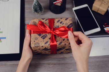 POV yüksek ilk kişi genel gider görüş açısı yakın güzel kırmızı kurdele fotoğrafı kadar yay unwrapped sarılmış kapalı paketi açmak elinde ahşap masa üzerinde kağıt