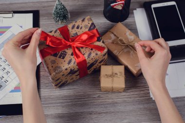 POV yüksek ilk kişi genel gider görüş açısı yakın güzel kırmızı kurdele fotoğrafı kadar yay unwrapped sarılmış kapalı paketi açmak elinde ahşap masa üzerinde kağıt