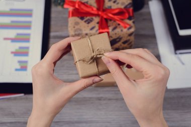 POV yüksek ilk kişi genel gider görüş açısı yakın güzel kırmızı kurdele fotoğrafı kadar yay unwrapped sarılmış kapalı paketi açmak elinde ahşap masa üzerinde kağıt
