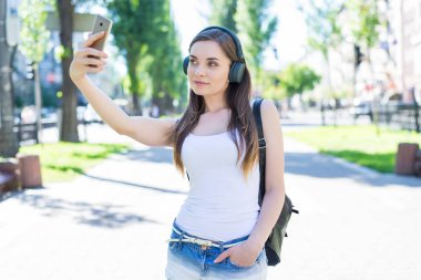 Instagram etki unsuru gadget aygıt öğrenci denim giysiler kavramı. Oldukça çekici güzel güzel kendine güvenen Bayan portresi fotoğraf yapmak selfie park şehir hafta sonu çekim almak turizm seyahat