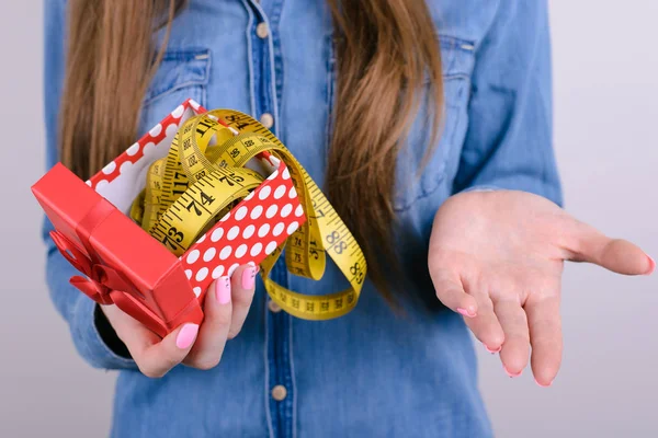 Bad unwanted unwished gift for people lady person concept. Cropped closeup photo of disappointed confused frustrated student holding showing tape measure in hand isolated grey background