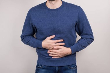 Alem yeme konsepti üzerinde overeating. Hazımsızlık izole gri arka plan ile hazımsızlık sorunu olan mutsuz üzgün üzgün ofis çalışanı kırpılmış yakın çekim fotoğraf portresi