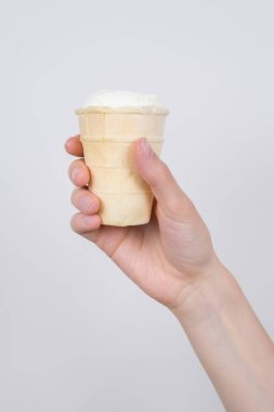 Dondurma izole gri arka plan ile lezzetli nefis lezzetli waffle fincan tutan el dikey fotoğraf