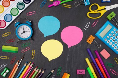 Okul konseptinde düşünceler ve fikirler. Yukarıda, tahtada izole edilmiş üç fikir baloncuğunun etrafındaki çok renkli kırtasiyenin yukarıdaki görünüm fotoğrafı.