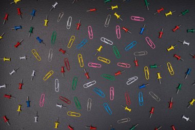 Kırtasiye konsepti. Yukarıda, karatahtaya izole edilmiş renkli raptiye ve raptiyelerin yukarıdaki görünüm fotoğrafı