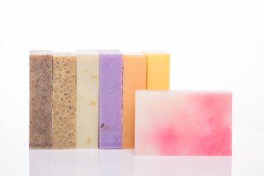 Organik el yapımı sabun konsepti. Beyaz arkaplanda izole edilmiş ev yapımı renkli sabun çubuklarının bir sıra fotoğrafı