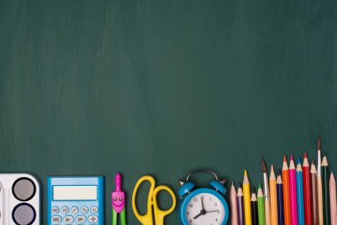 Okul konseptine geri dönelim. Yukarıda yeşil tahtada izole edilmiş renkli kırtasiyelerin yukarıdaki görünüm fotoğrafı