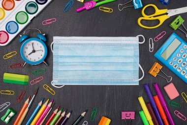 Sosyal uzaklık kavramı. Üst tepedeki renkli kırtasiyenin karatahtaya izole edilmiş yüz maskeli resmi