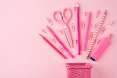 Okul ve ofis kırtasiyesi kavramı. Sağ tarafa yerleştirilmiş pembe kırtasiyenin yukarıdaki yukarıdaki görünümü fotosu. Telif alanı olan, pastel pembe arka planda izole edilmiş.